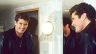 David Hasselhoff blickt 1990 bei einem Fotoshooting in London in den Spiegel