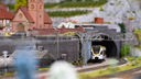 Modellbau: Ein Zug der Eurobahn fährt auf Schienen durch einen Tunnel in einer Miniaturlandschaft.
