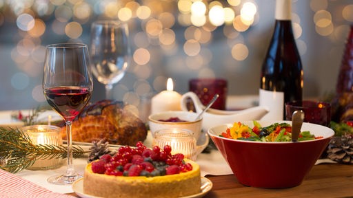 Eine Flasche und Glas Rotwein auf einem festlich gedeckten Weihnachtstisch
