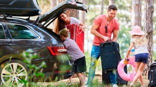 Eine Familie packt ihr Auto und macht Urlaub.