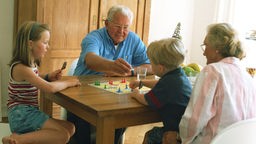 Großeltern spielen mit ihren Enkeln ein Brettspiel.