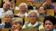 Lebenslanges Lernen, ältere Menschen über 60 Jahre sitzen in einem Hörsaal der Universität