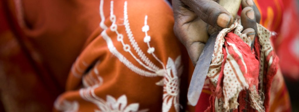 Das Beitragsbild WDR5 Dok5 "Perle – Der Weg zurück zur körperlichen Unversehrtheit" zeigt eine ehemalige Beschneiderin die ein rostiges Messer in der Hand hält.