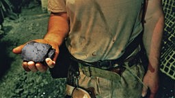 Symbolbild Bergbau im Ruhrgebiet: Ein Bergarbeiter hält ein Stück Kohle in der Hand.