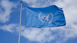 Vor einer weissen Wolke weht die Fahne der Vereinten Nationen in Bonn.