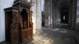 Ein hölzerner Beichtstuhl im spärlichen Licht der Kirche St. Maria im Kapitol. Die Kirche gehört zu den Kölner Kirchen, die im Zweiten Weltkrieg schwere Schäden davon getragen haben.