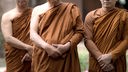 Symbolbild: Ein buddhistischer Meister steht inmitten zweier Schüler: Sie verschränken ihre Arme vor dem Körper, die Gesichter sind im Bildausschnitt nicht zu sehen.