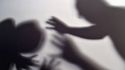 Gestelltes Bild zum Thema häusliche Gewalt - Schatten sollen symbolisieren, wie sich eine Frau versucht, sich vor der Gewalt eines Mannes zu schützen.