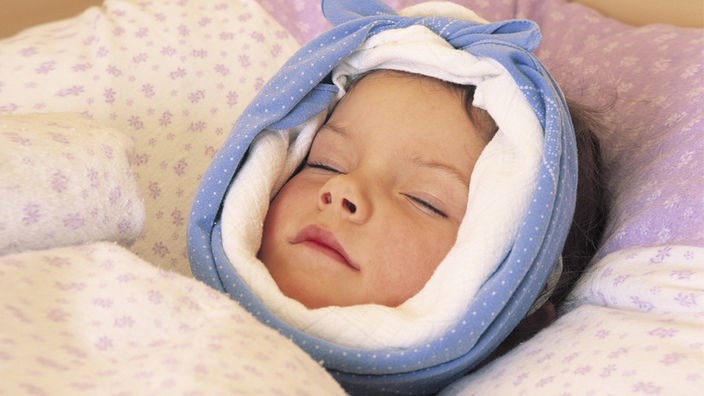 Ein Kleinkind mit Mumps liegt im Bett mit Kopfwickel