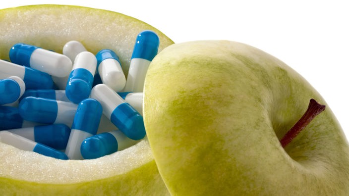 Symbolfoto Vitamintabletten: In einem ausgehölten Apfel liegen Tablettenkapseln. 