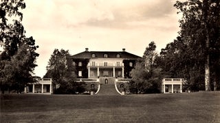 Schwarz-weiß-Fotografie zeigt einen Gutshof mit eleganter Außentreppe in einem Park