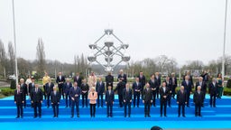 Staats- und Regierungschefs stehen für ein Gruppenfoto vor dem Atomium, einer Skulptur atomarer Verbindungen