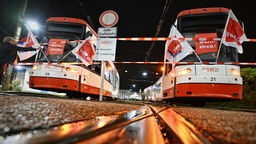 Straßenbahnen mit Verdi-Plakaten und -Flaggen stehen vor einem Depot der Dortmunder Verkehrsbetriebe DSW21. 