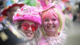 Zwei Karnevalistinnen mit pinkem und buntem Makeup lachen in die Kamera