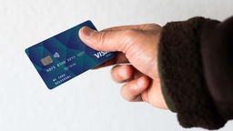 Ein Mensch hält eine Bezahlkarte in der Hand.