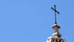 Symbolbild: Ein christliches Kreuz auf einem Kirchturm in Lissabon.