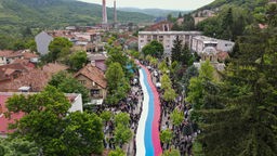  Menschen halten eine riesige serbische Flagge bei einer Demonstration gegen den ethnisch-albanischen Bürgermeister in Zvecan im Nordkosovo. (31.05.2023)