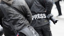 Ein Fotoreporter trägt einen Aufnäher mit dem Text "PRESS" auf seiner Jacke. Symbolbild
