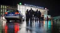 Polizisten stehen neben einem Einsatzwagen vor dem Kölner Hauptbahnhof