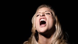 Symbolbild: Ein Mensch hat den Mund zum Gesang oder Schrei weit geöffnet.