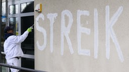 Symbolbild: Maler überdecken am städtischen Nord-Ost-Bad einen schwarzen Schriftzug «Streik» mit weißer Farbe, um anschließend die komplette Wand flächendeckend neu zu streichen. 