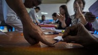 Ein Wahlhelfer markiert einen Finger mit unauslöschlicher Tinte, nachdem die Person Ihre Briefwahlstimme für die bevorstehenden Parlamentswahlen abgegeben hat. 