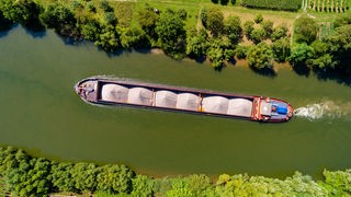 Ein Schiff transportiert Güter auf einem schmalen Fluss.