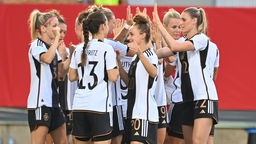 Mehrere Spielerinnen der deutschen Frauen-Fußball-Nationalmannschaft stehen jubelnd zusammen auf dem Fußballfeld.