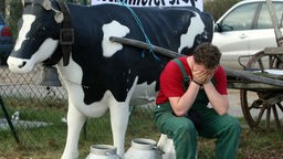 Symbolbild Landwirte im Burnout: Ein Landwirt sitzt und hält die Hände vor sein Gesicht.