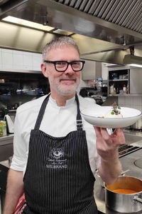 Sternekoch Christopher Wilbrand in seiner Küche mit einem Teller Linsensalat
