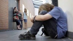 Ein Junge wird von Mitschuelerinnen gehaenselt . Symbolbild zum Thema Mobbing an der Schule.
