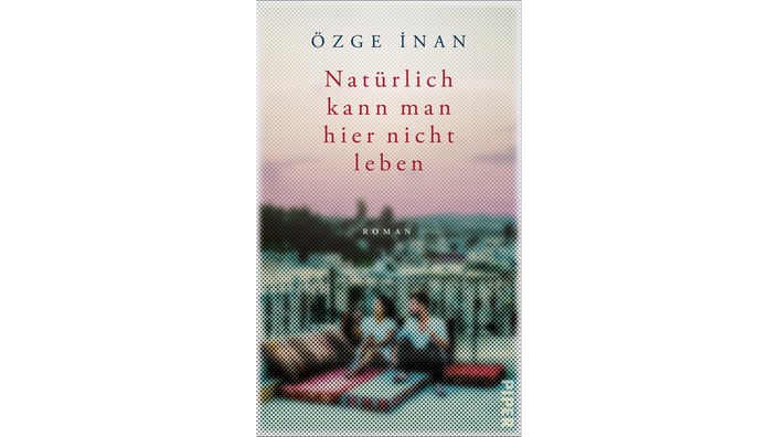 Das Buchcover von Özge İnans "Natürlich kann man hier nicht leben" sieht man zwei Menschen auf einem flachen Dach eines weißen Hauses sitzen unter dem Himmel sitzen.