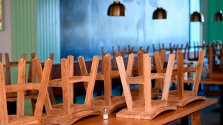 Geschlossenes Restaurant: Stühle stehen verkehrtherum auf Tischen.
