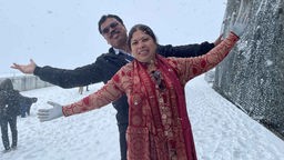 Eine indische Frau im Sari und ein indischer Mann im Anzug im Schnee auf der Aussichtsplattform auf dem Jungfraujoch (Schweiz)