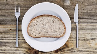 Symbolbild Verzicht: Eine trockes Brotscheibe liebt auf einem Teller.