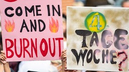 Schildern mit der Aufschrift "Come in and Burnout" und "4 Tage Woche?" bei einer Demonstration von Ärzten in Berlin.