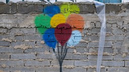 Symbolbild für Angst und Hoffnung: Bunte Luftballons auf eine Mauer gemalt