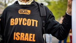 Ein Mann trägtr während einer Demonstration ein T-Shirt mit der Aufschrift "BDS - Boycott Israel Apartheid"