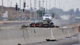Israelische Soldaten gehen auf einer Straße in Deckung.