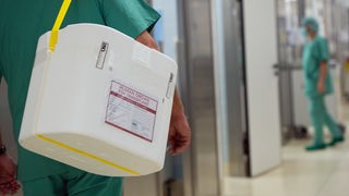 Ein Styropor-Behälter zum Transport von Organen wird an einem OP-Saal vorbeigetragen.