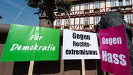 Hessen, Wolfhagen: Schilder mit der Aufschrift "Für Demokratie", "Gegen Rechtsextremismus" und "Gegen Hass" stehen während einer Mahnwache anlässlich des Mordes am Kasseler Regierungspräsidenten Walter Lübcke (CDU) auf dem Marktplatz. 