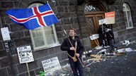 Mit der Landesfahne protestiert ein Isländer vor dem Parlament "Althing" in Reykjavik 