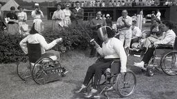 Zwei im Rollstuhl sitzende Frauen beim Fecht-Wettkampf der Stoke Mandeville Games 1955