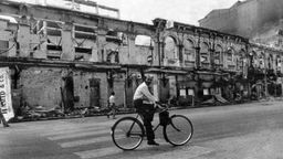 Ein Radfahrer am 4. August 1983 in Sri Lankas Hauptstadt Colombo vor zerstörten Häusern, die von Tamilen bewohnt waren