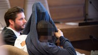 Der 26-jährige Angeklagte sitzt am 06.05.2016 im Amtsgericht in Köln (Nordrhein-Westfalen) neben seinem Verteidiger Bernhard Scholz auf der Anklagebank und zieht sich einen Pullover über