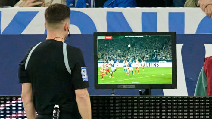 Schiedsrichter Harm Osmers betrachtet die Videobilder und nimmt in der Nachspielzeit einen Elfmeter für Schalke und eine Gelb-Rote Karte für den vermeintlichen Übeltäter zurück. 
