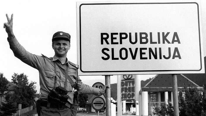  Ein Kommandant einer slowenischen Polizei Sonderheiten macht das Viktoria-Zeichen am 29. Juni 1991, neben einem Schild "Republik Slowenien"
