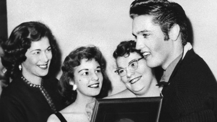 Elvis Presley mit seiner ersten Goldenen Schallplatte für den Titel "Heartbreak Hotel" und weiblichen Fans (1956)