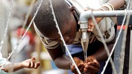 Ein Junge, trinkt in einem Flüchtlingslager der UN gereinigtes Trinkwasser 