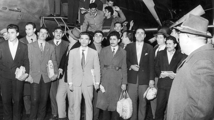 Türkische Gastarbeiter nach Ankunft vor einem Flugzeug